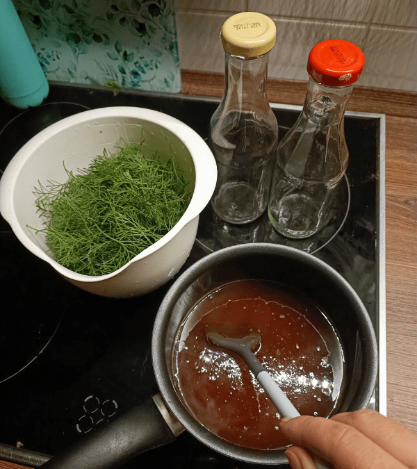 Jedna osoba připraví sirup pro bylinu cola. Rulík je připraven v bílé misce.